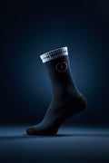 Black sock with a white logo on a wooden floor